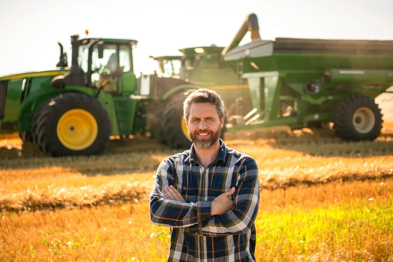 Imagem de um produtor em frente a máquinas agrícolas, simbolizando o consórcio rural para aquisição de bens.