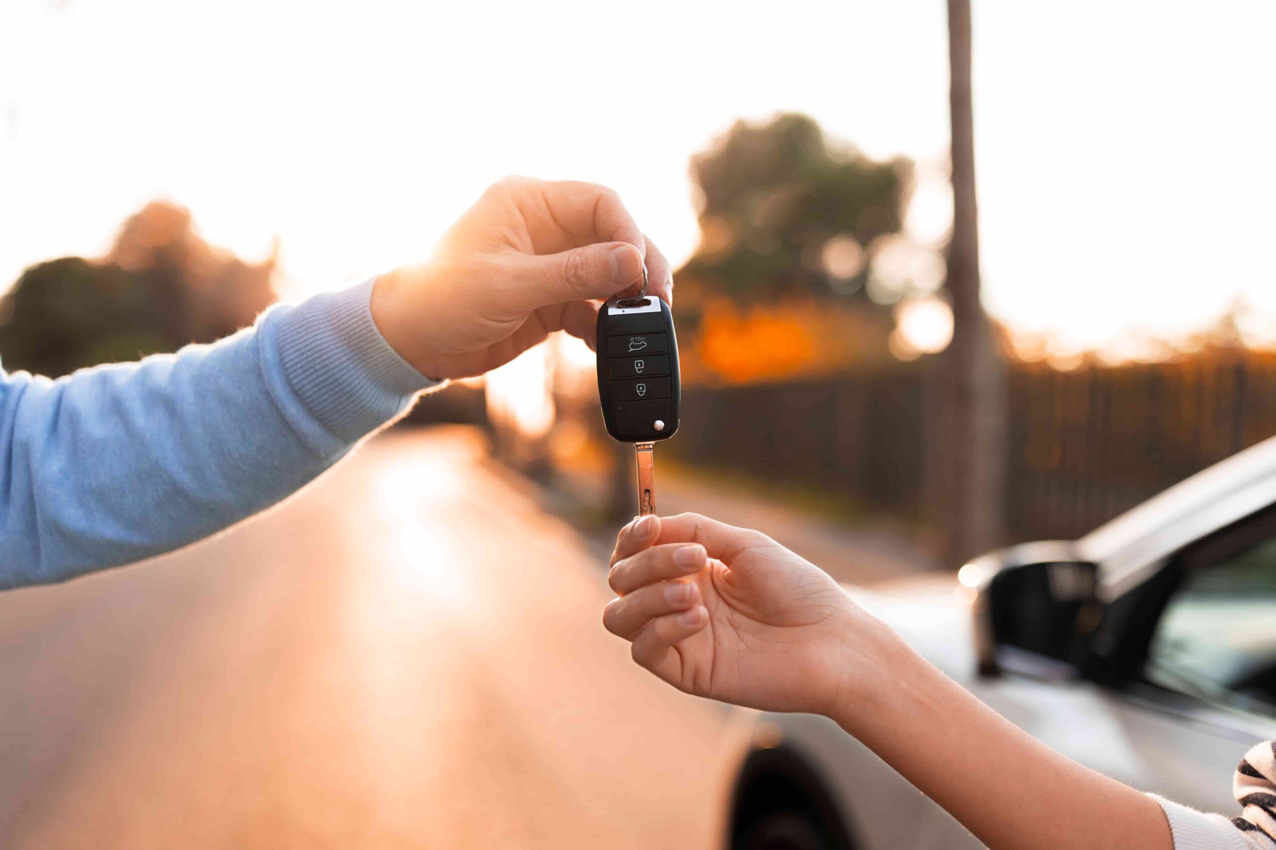 Imagem de uma pessoa passando a chave do automóvel para outra, simbolizando o consórcio de carros usados.