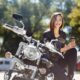 Mulher sorri e segura um capuccino sentada em sua moto adquirida pelo consórcio de motos